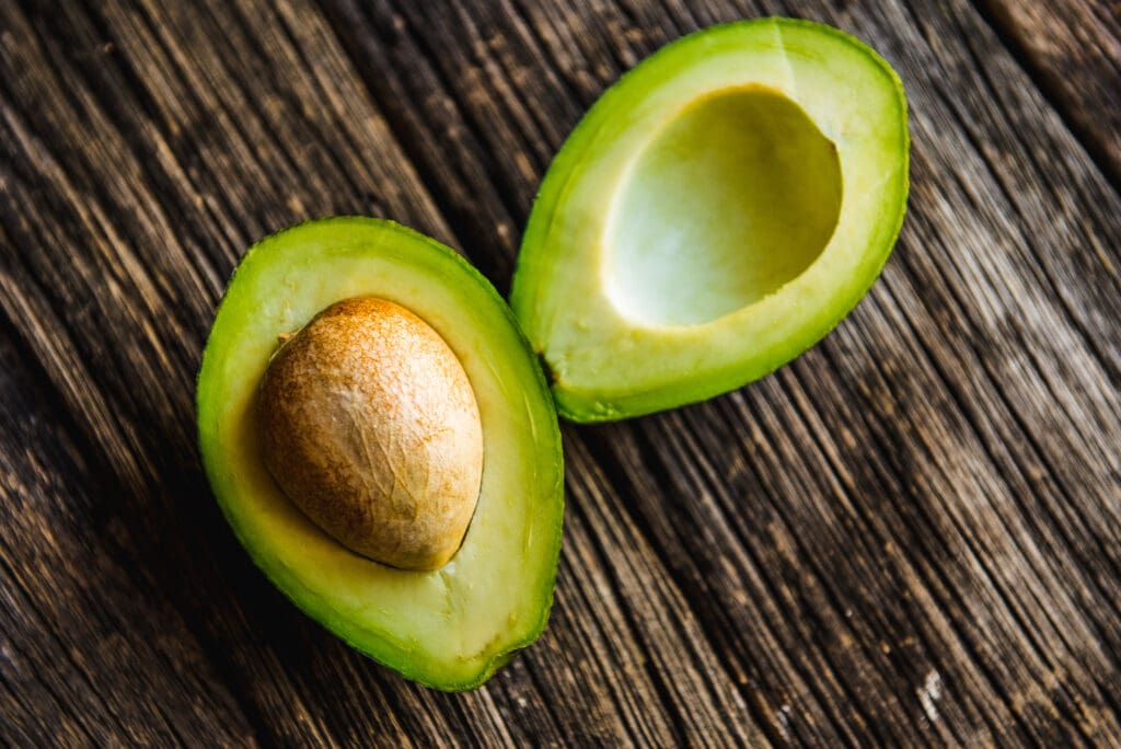 Fresh Avocado sliced over vintage wooden background close up.